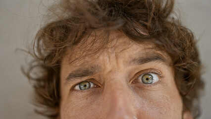 Close-up portrait of a young man with curly hair and captivating eyes against a white background.