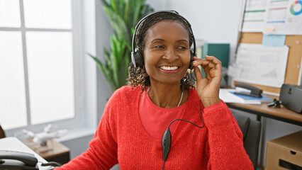 Smiling african woman with headphones in modern office workplace.