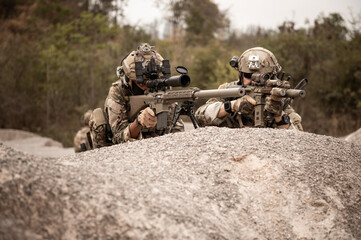Soldiers in camouflage uniforms aiming with their rifles.ready to fire during military operation in...