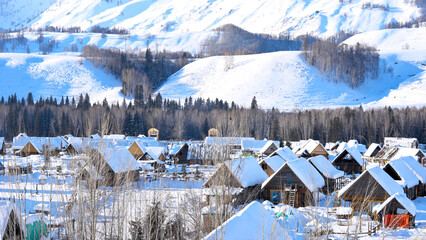 Log cabin village in winter, houses on hill neighborhood blanketed with snow in Xinjiang, China,...