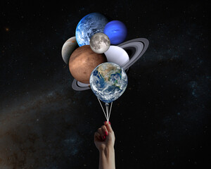 Hand with planets shaped balloons in solar system. Elements of this image furnished by NASA.