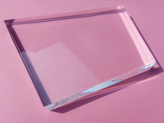 a rectangular clear acrylic plastic thick on a pink surface