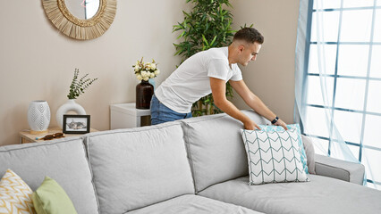 Handsome man arranging pillow on couch in a modern living room interior