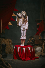 Siamese twin girls in white vintage costumes with makeup standing on stage over dark retro circus backstage background. Concept of circus, theater, performance, show, retro and vintage © master1305