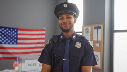 Smiling african american police officer in uniform against us flag in voting center.