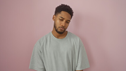 Portrait of a contemplative young african american man against a pink background, exuding a sense of introspection and casual style.