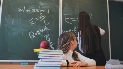 Two high school girls at the blackboard in their class.