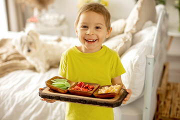 Cute little preschool child, boy, eating dried fruits at home, strawberries, melon, pineapple