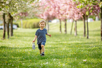 Beautiful blond child, boy, drinking water in the park on a hot day