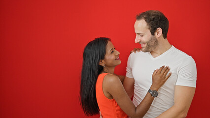 Beautiful couple smiling confident hugging each other over isolated red background