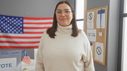 Hispanic senior woman smiling in a usa electoral center with american flags and vote banners