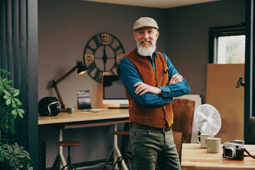Portrait d'un homme debout souriant quinquagénaire senior hipster élégant et stylé qui fait une pause dans un atelier créatif vintage