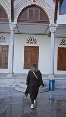 A young woman explores the historic grounds of istanbul's ottoman-era topkapi palace, evoking travel and culture.