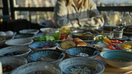 A young woman enjoys a traditional turkish breakfast at a restaurant with a view of the hagia sophia in istanbul.