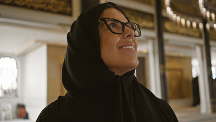 Smiling woman wearing hijab inside ornate qatari mosque with islamic architecture visible.