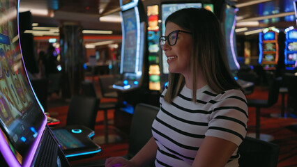 Smiling woman playing slot machine at a vibrant casino, epitomizing leisure, excitement, and...