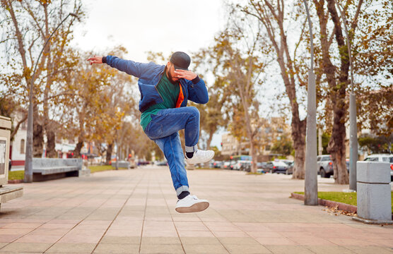 latin American breakdancer performing foot movements or toprock in the air on the street