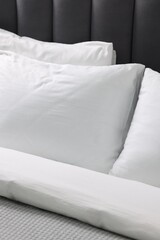 Fototapeta na wymiar Soft white pillows and duvet on bed, closeup