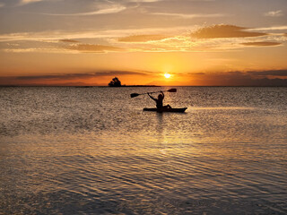 Happy Woman Silhouette Rowing in a kayak at sunset