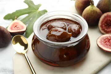 Jar of tasty sweet jam and fresh figs on white marble table