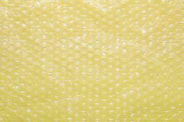 Transparent bubble wrap on yellow background, top view