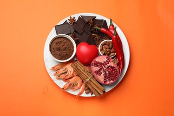 Natural aphrodisiac. Different products and heart model on orange background, top view