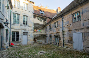 A nice old courtyard in the small city. There are houses and stone pavement overgrown with green moss.