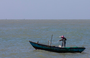 Fisherman fishing with a net from a boat