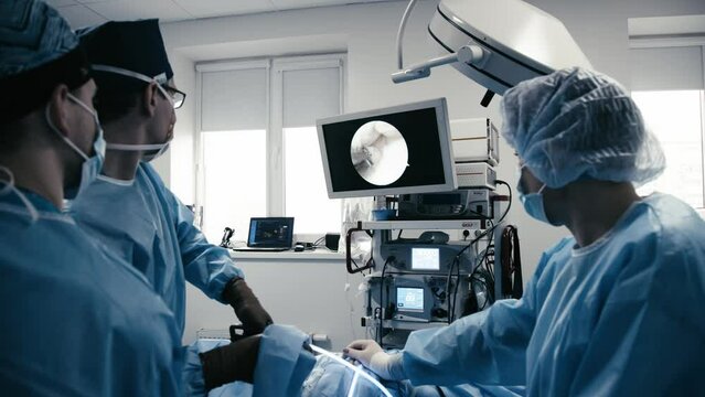Professional surgeons perform the operation in a modern surgical operating room and monitor the process in front of monitors. Modern medical technologies, operation and surgery department.