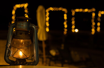 Lantern lit with a candle by a beach.