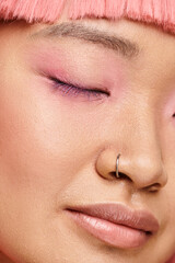 close up of pretty young woman closed eye with perfect skin, pink makeup and nose piercing