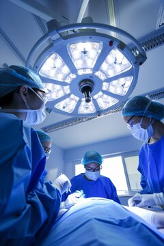 Low angle view of three surgeons under surgery lights in operating theatre