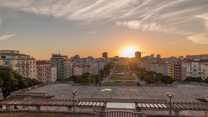 Obraz premium Panorama showing sunset over lawn at Alameda Dom Afonso Henriques and the Luminous Fountain aerial timelapse in Lisbon.