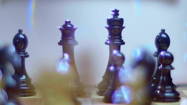 Lacquered chess pieces sparkle in the ray of light and the light source creates a beautiful rainbow flare. Closeup