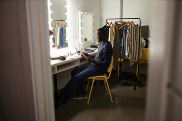 Wide angle shot of Black adult man reading script and rehearsing lines backstage copy space