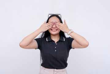 Youthful Asian woman smiling with hands covering her eyes, isolated on white