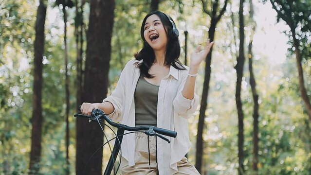 Attractive young woman in a hat riding a bicycle in a park. Active people. Outdoors