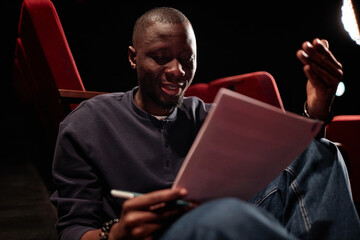 Portrait of smiling African American man reading lines emotionally while rehearsing for performance