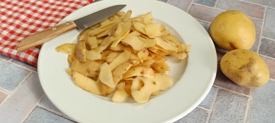 Fotobehang épluchure de pommes de terre, en gros plan, dans une assiette © ALF photo
