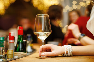 A girl in a bar drinks white wine at the bar counter.