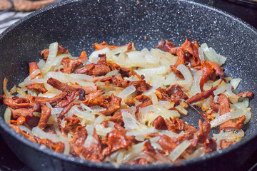 We cook mushrooms. Fried mushrooms with onions in a frying pan close up.