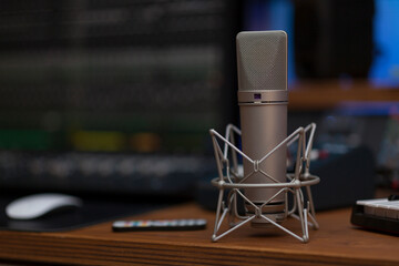 Close up on a high end studio microphone, background is a blurred studio environment, no people are visible.