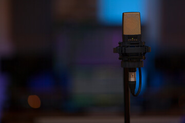 Close up on a high end studio microphone, background is a blurred studio environment, no people are visible. - 765025732