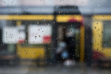 closeup of the rain drops of the window at the tramway station in the street - 765029912