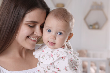 Happy young mother with her baby daughter at home, closeup