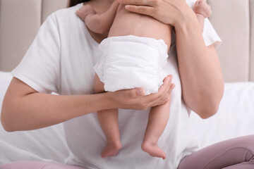 Obraz na płótnie Canvas Mom holding her baby in diaper at home, closeup