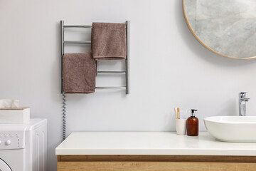 Heated towel rail with brown towels in bathroom - obrazy, fototapety, plakaty