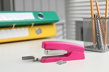Stapler and metal staples on white table indoors
