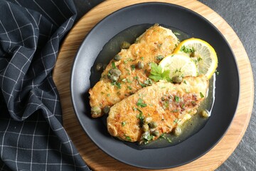 Delicious chicken piccata on black table, top view