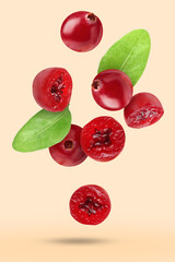 Fresh red cranberries and green leaves falling on beige background
